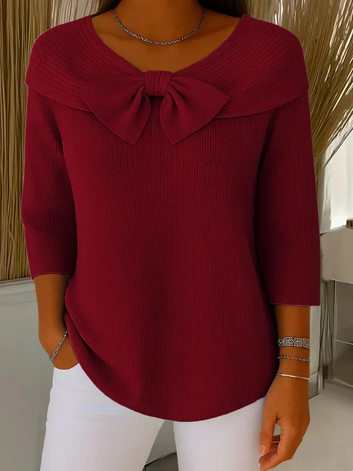A woman wearing a shaped jumper with a soft bow detail, styled for a coffee date.