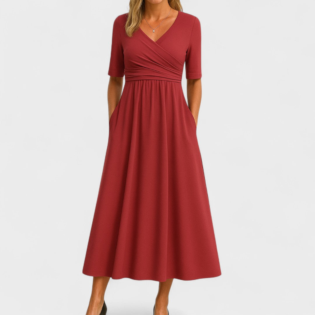 Woman wearing a mid-calf dress with a crossover V-neckline, gathered waist and gently flared skirt.