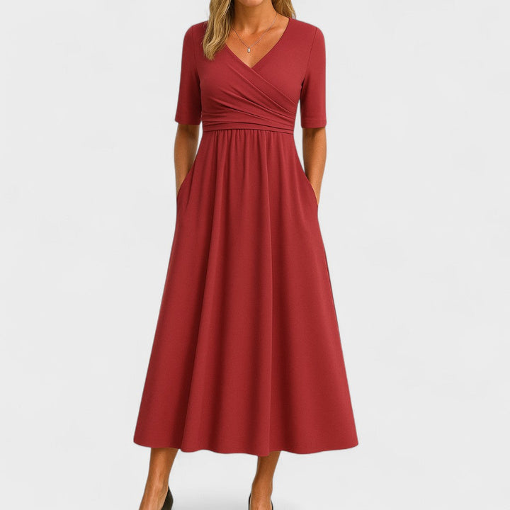Woman wearing a mid-calf dress with a crossover V-neckline, gathered waist and gently flared skirt.