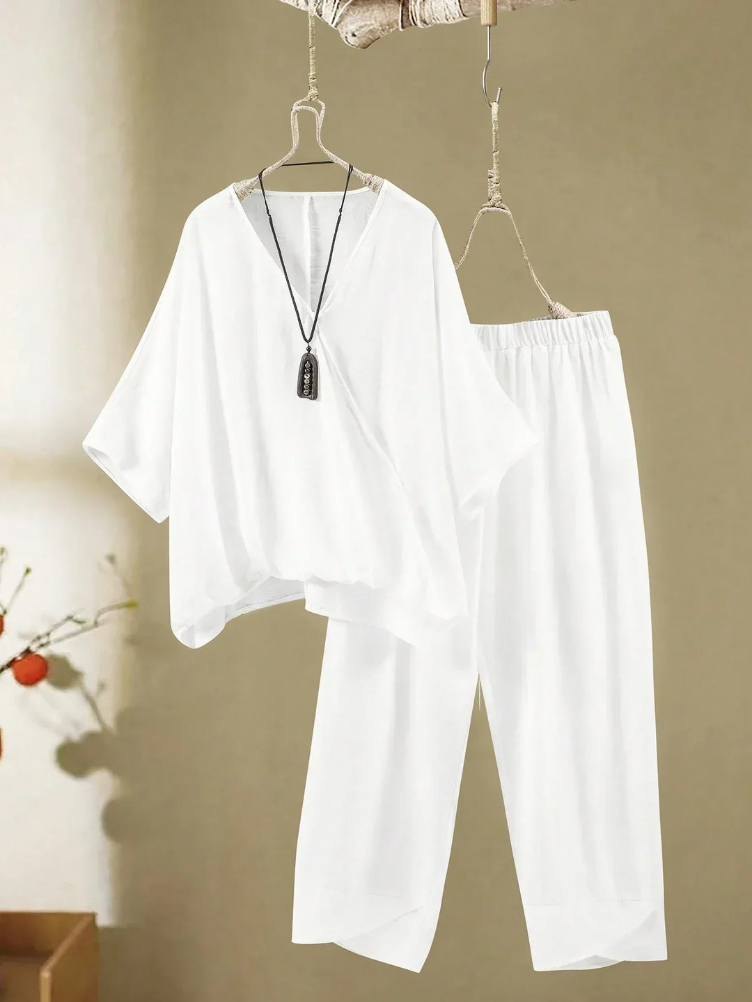 A woman wearing a flowing V-neck knot-detail top with matching flared trousers.