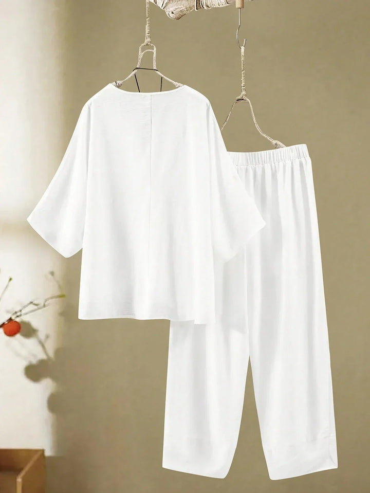 A woman wearing a flowing V-neck knot-detail top with matching flared trousers.