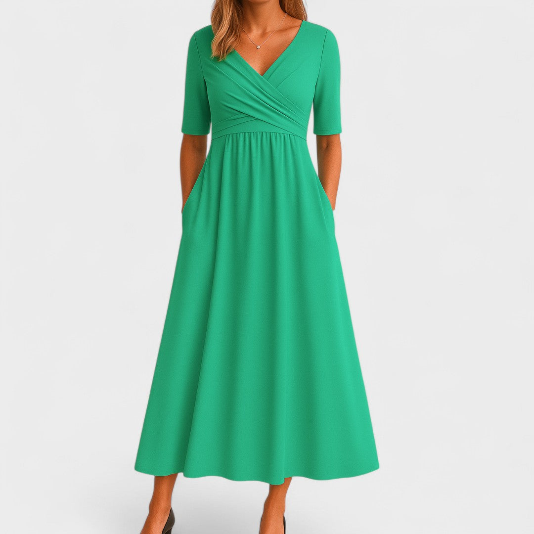 Woman wearing a mid-calf dress with a crossover V-neckline, gathered waist and gently flared skirt.