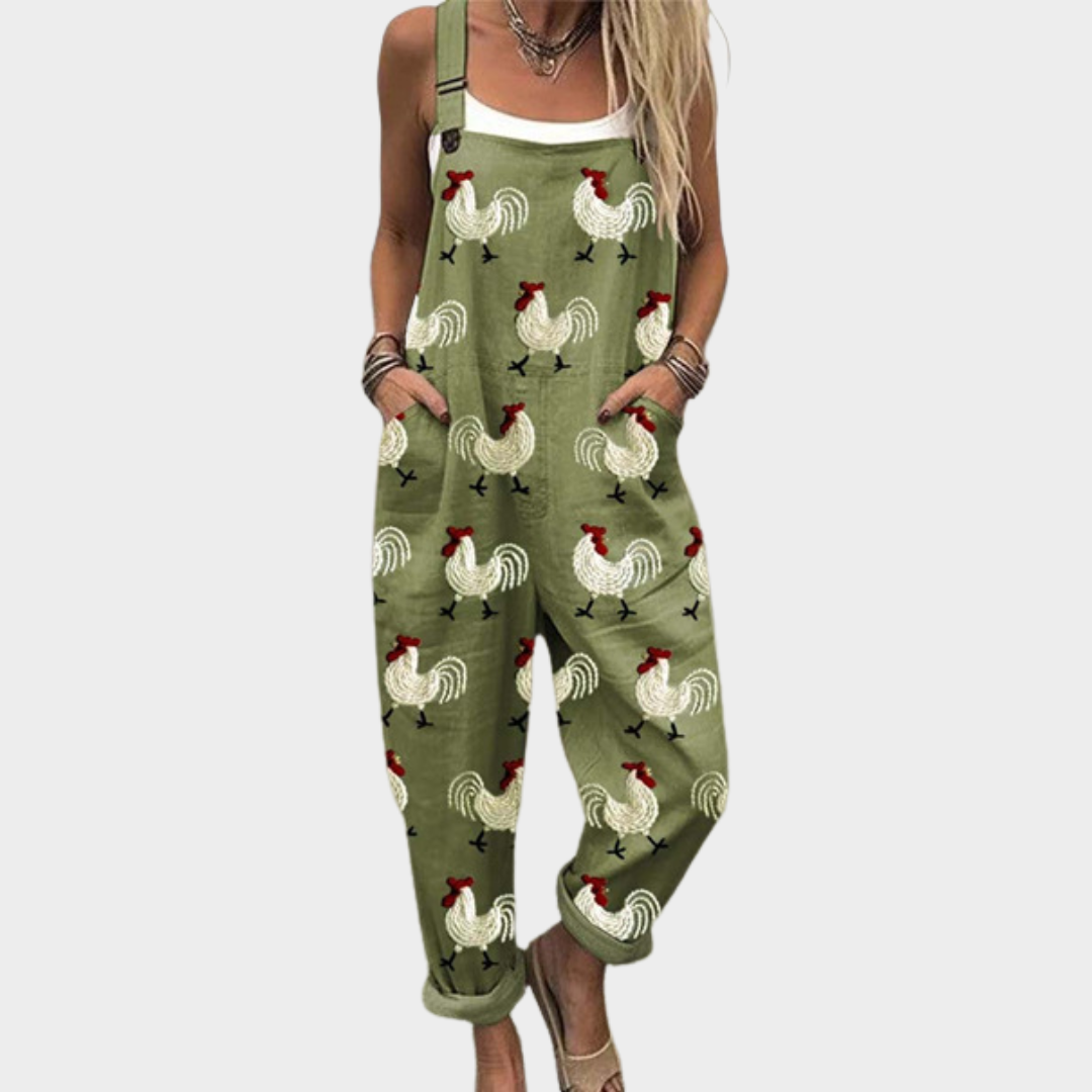 Woman wearing relaxed olive green dungarees with a playful hen and cockerel print, side pockets and adjustable straps