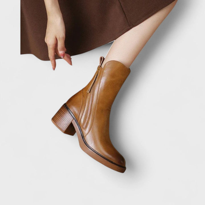 Woman wearing black refined ankle boots with tailored trousers in a city setting.