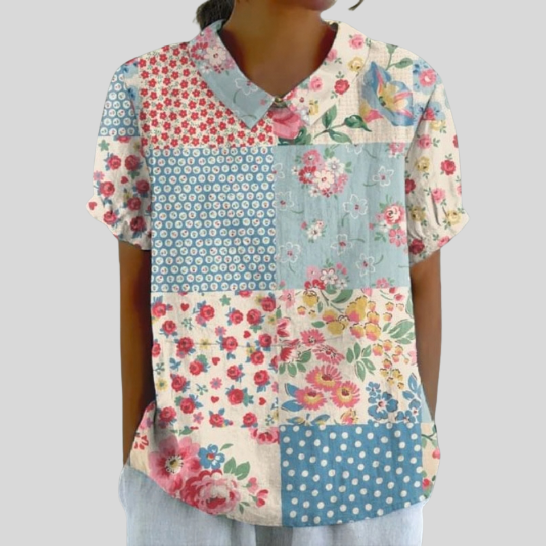 A woman wearing a floral top with a chic collar, at ease at a relaxed garden gathering.