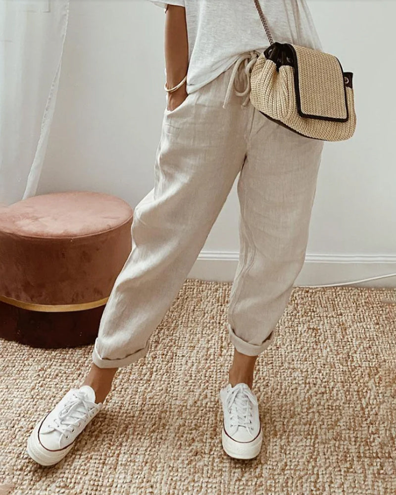 A woman wearing flowing elegant trousers with a soft elastic waist and deep pockets.