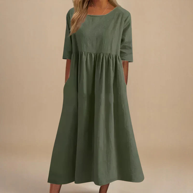 A woman wearing the Carmel flowing day dress with a gathered waist and elbow-length sleeves.