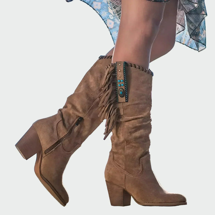 Woman wearing fringed boho-Western ankle boots with a floaty dress at a festival.