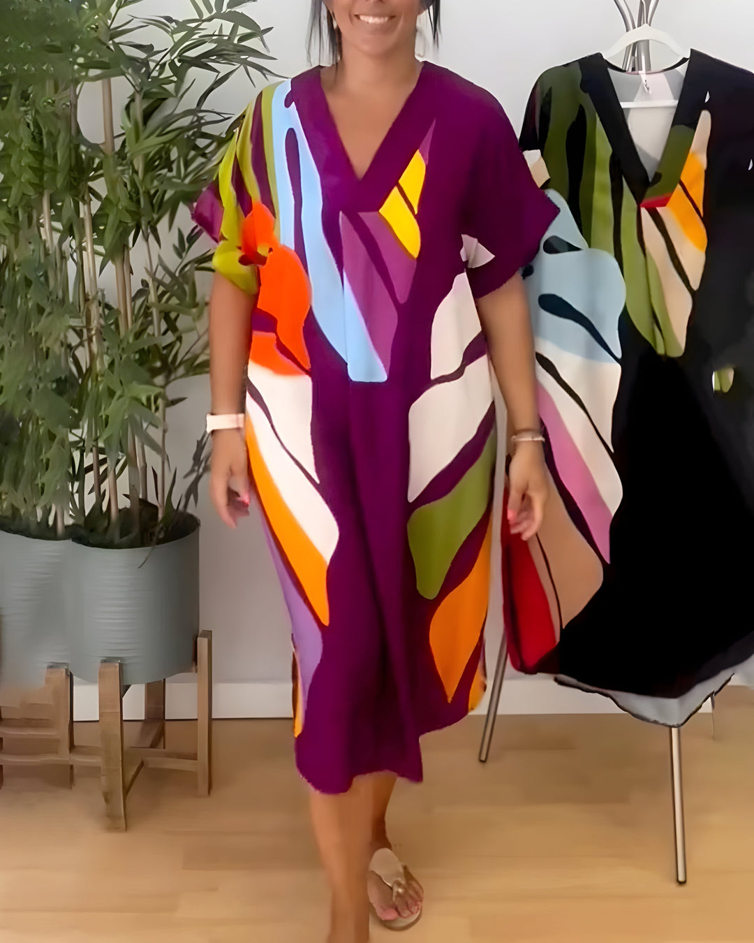 A woman wearing a colourful abstract print dress with a V-neckline and short sleeves.