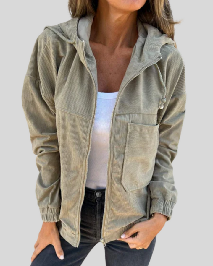 A woman wearing a zip-up hooded gilet with a soft ribbed texture, layered over a jumper.