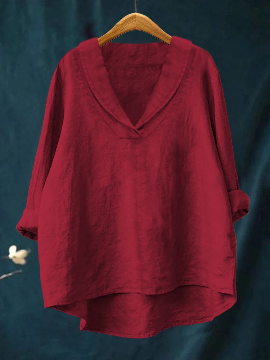 A woman wearing an elegant plain summer blouse with a flowing drape, styled with trousers.
