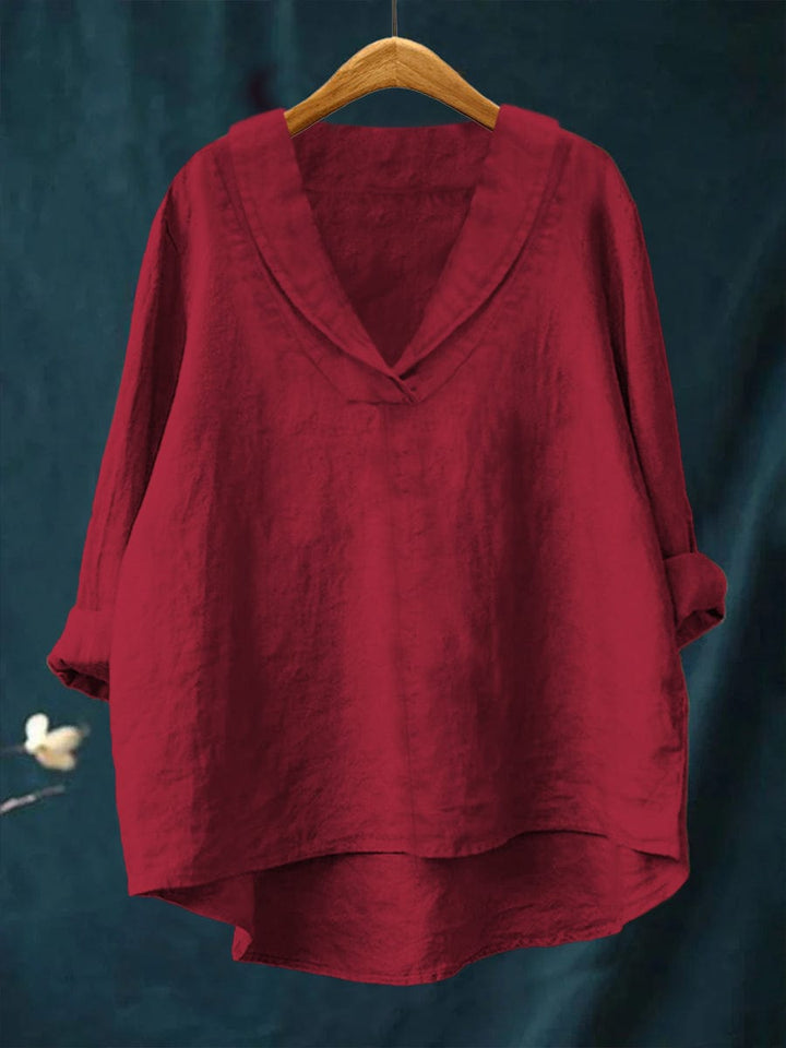 A woman wearing an elegant plain summer blouse with a flowing drape, styled with trousers.