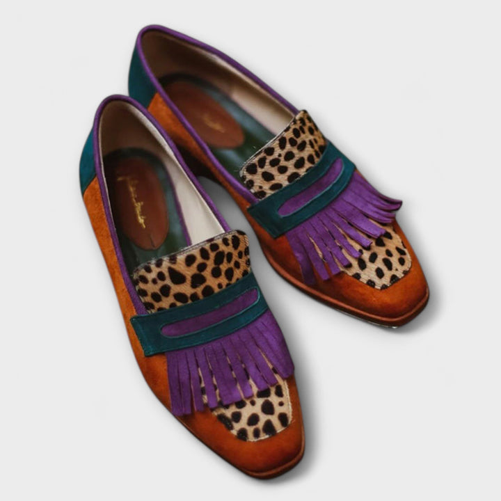 A woman wearing warm brown leopard-print loafers with autumn trousers, looking elegant and at ease.
