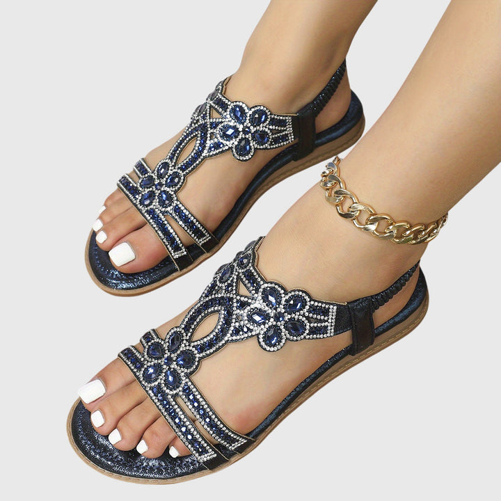 A woman wearing elegant gold open-front sandals with supportive straps and a cushioned sole.