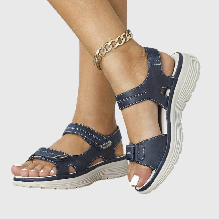 A woman in beige adjustable strap sandals standing steady and relaxed on a sunny path.