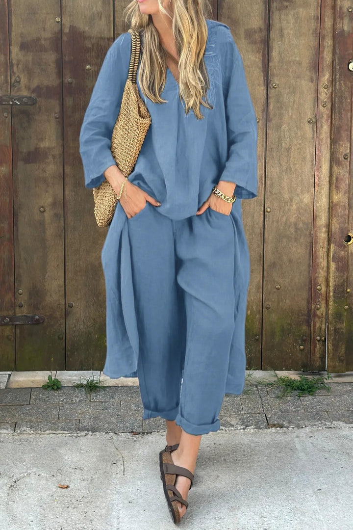 A woman wearing a blue asymmetric tunic with wide-leg trousers