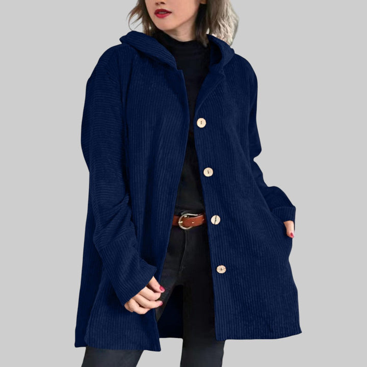 A woman wearing a hooded textured jacket outdoors in autumn