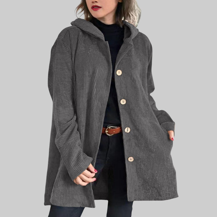 A woman wearing a hooded textured jacket outdoors in autumn