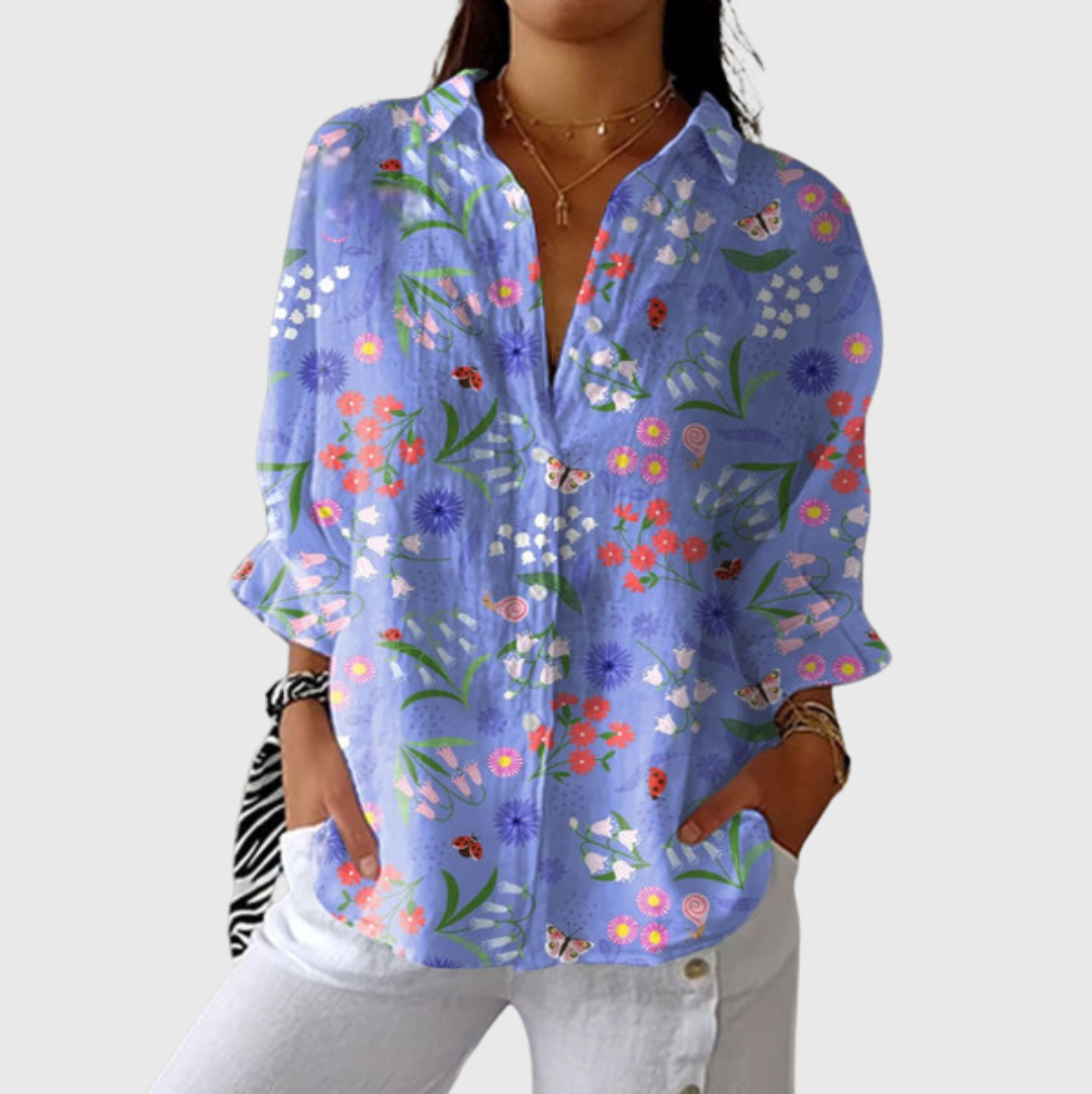 A woman wearing a relaxed colourful printed blouse with an elegant button front, styled with trousers for a comfortable day out.