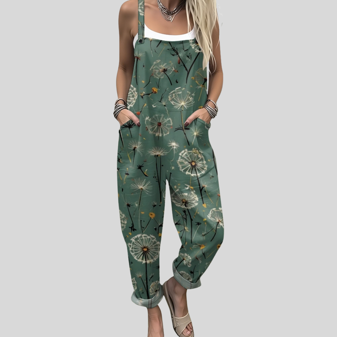 Bright mid-green dungarees with a scattered dandelion clock print showing full seed heads and drifting seeds, adjustable shoulder straps.