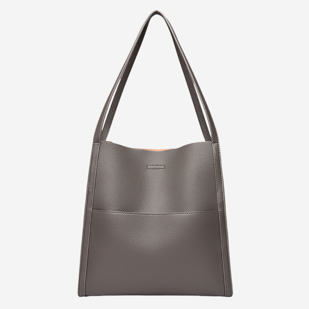 A woman carrying an elegant shoulder bag with clean lines over one shoulder in town