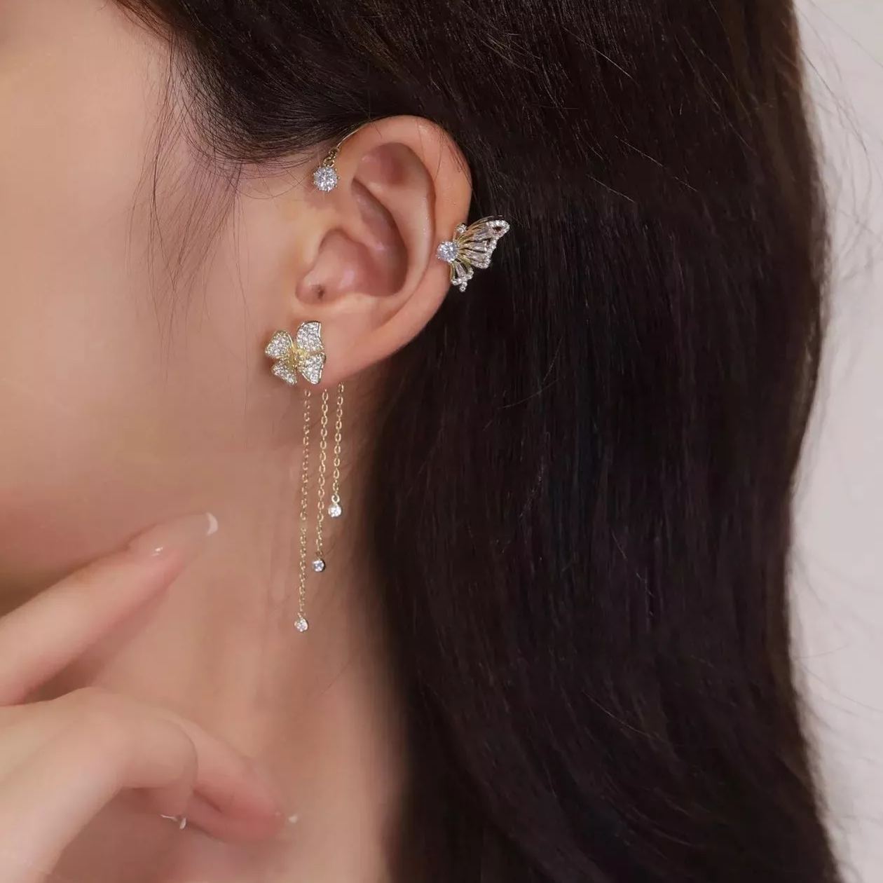 Gold celestial arc earring with a butterfly detail, framing the ear with sparkling luminosity