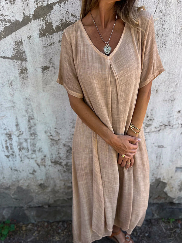 Woman wearing the Dolores™ flowing V-neck dress with short sleeves, standing relaxed in warm sunlight.