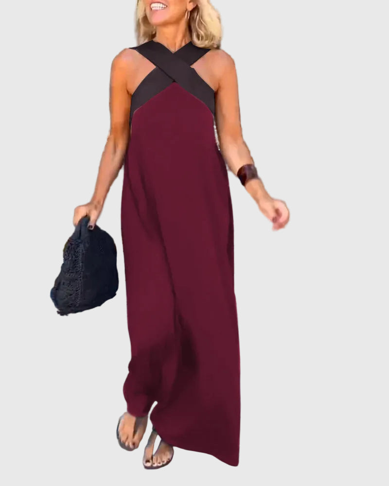 Woman wearing the Mary halterneck maxi dress in navy with a contrast crossover neckline, walking outdoors.