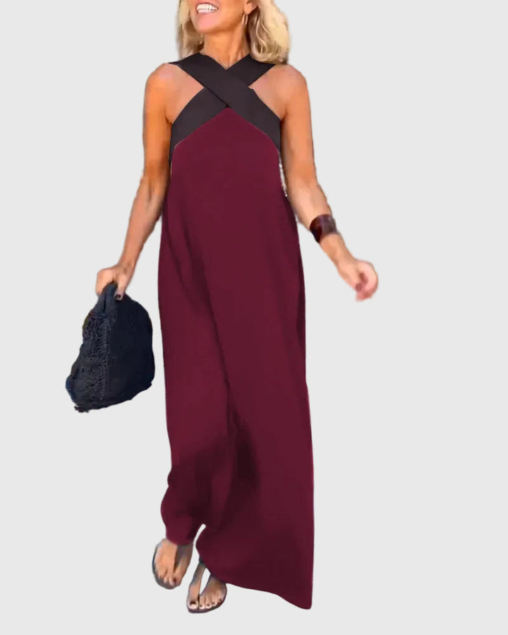 Woman wearing the Mary halterneck maxi dress in navy with a contrast crossover neckline, walking outdoors.