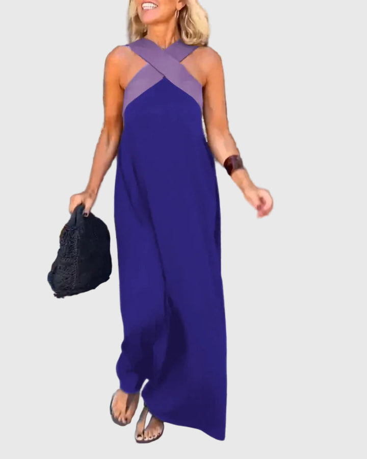 Woman wearing the Mary halterneck maxi dress in navy with a contrast crossover neckline, walking outdoors.