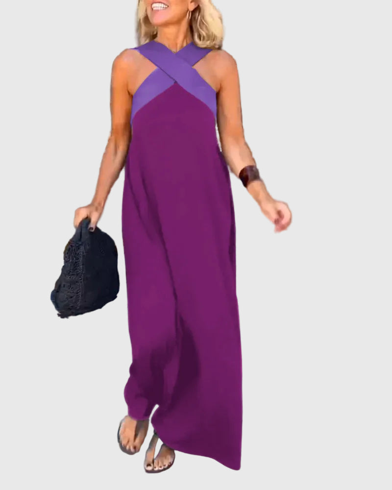 Woman wearing the Mary halterneck maxi dress in navy with a contrast crossover neckline, walking outdoors.