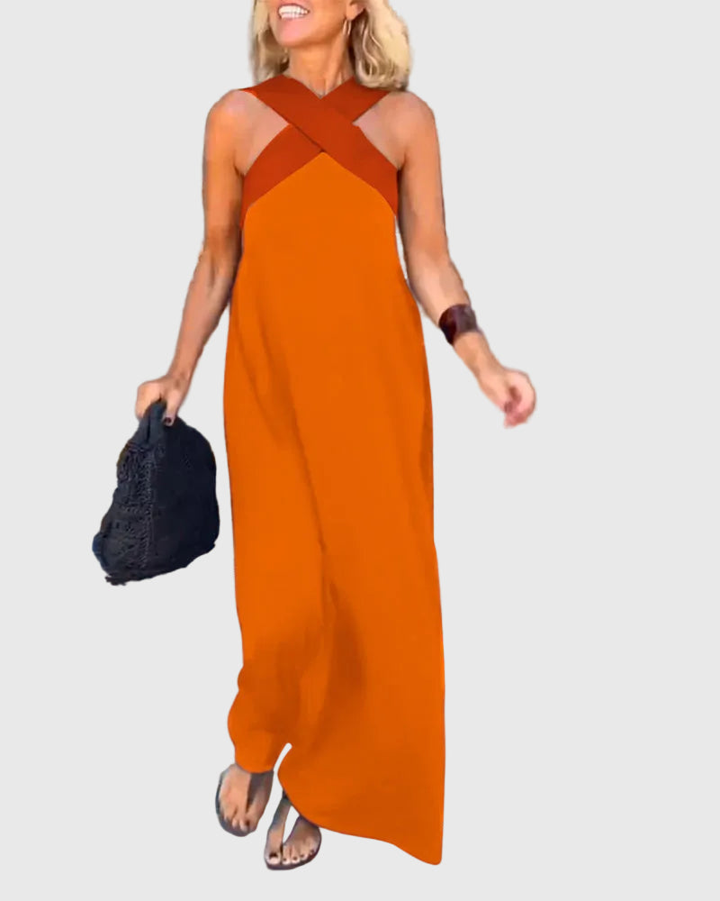 Woman wearing the Mary halterneck maxi dress in navy with a contrast crossover neckline, walking outdoors.