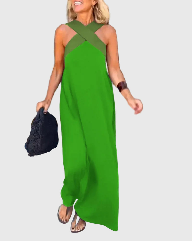 Woman wearing the Mary halterneck maxi dress in navy with a contrast crossover neckline, walking outdoors.