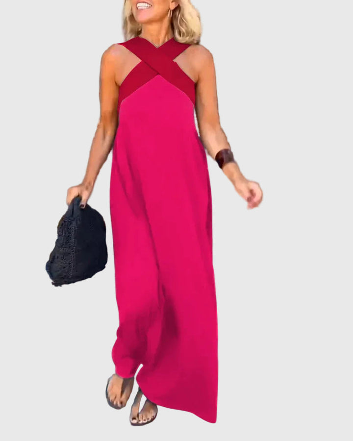 Woman wearing the Mary halterneck maxi dress in navy with a contrast crossover neckline, walking outdoors.