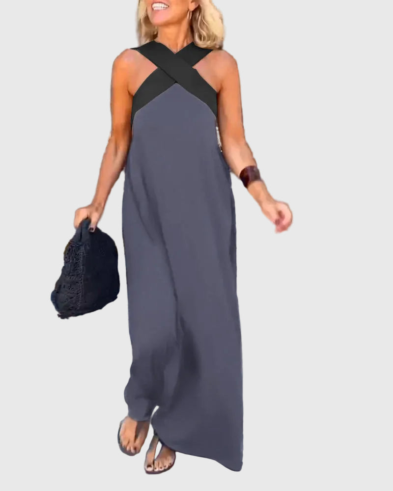 Woman wearing the Mary halterneck maxi dress in navy with a contrast crossover neckline, walking outdoors.