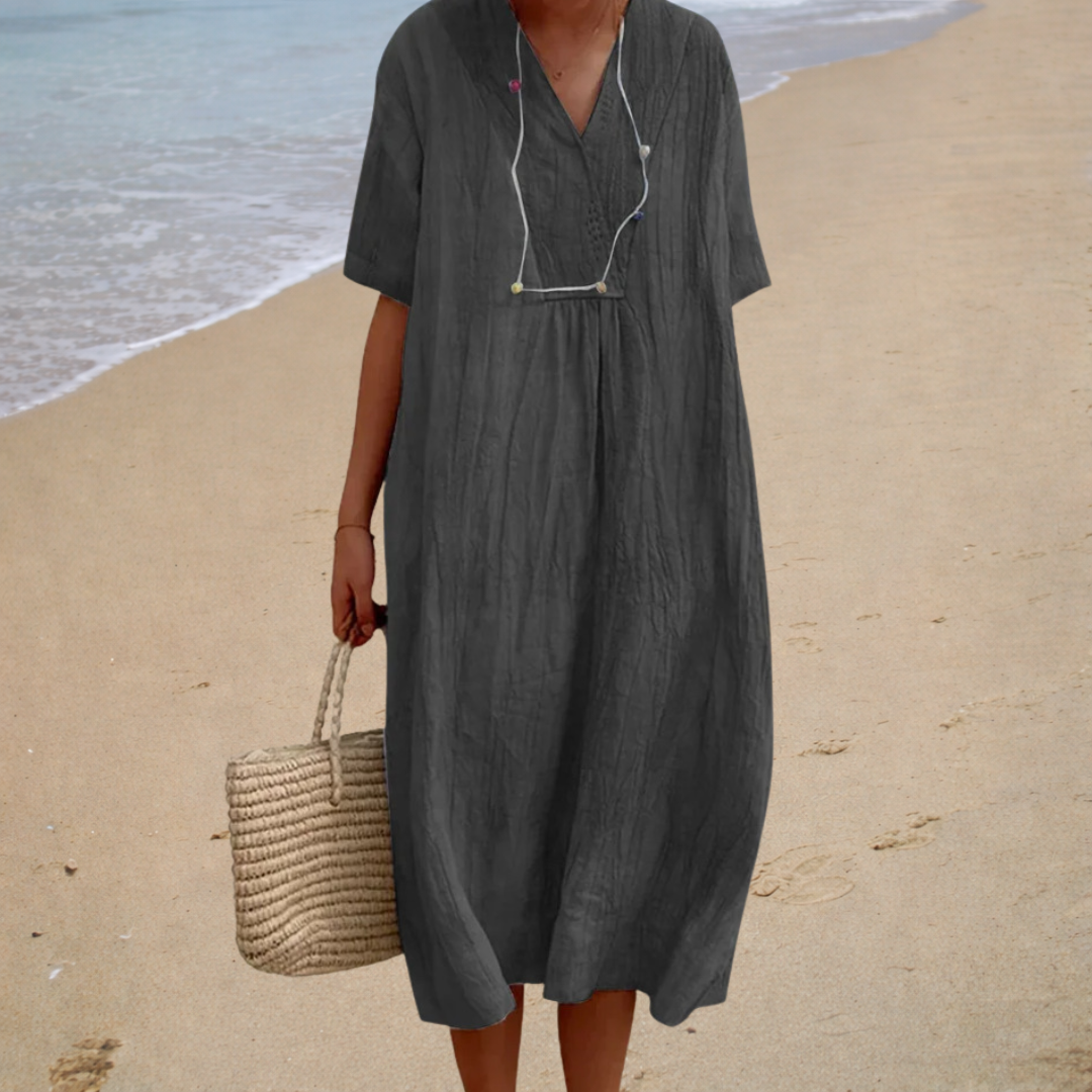A woman wearing a light, solid-coloured summer dress with a relaxed, flowing shape.