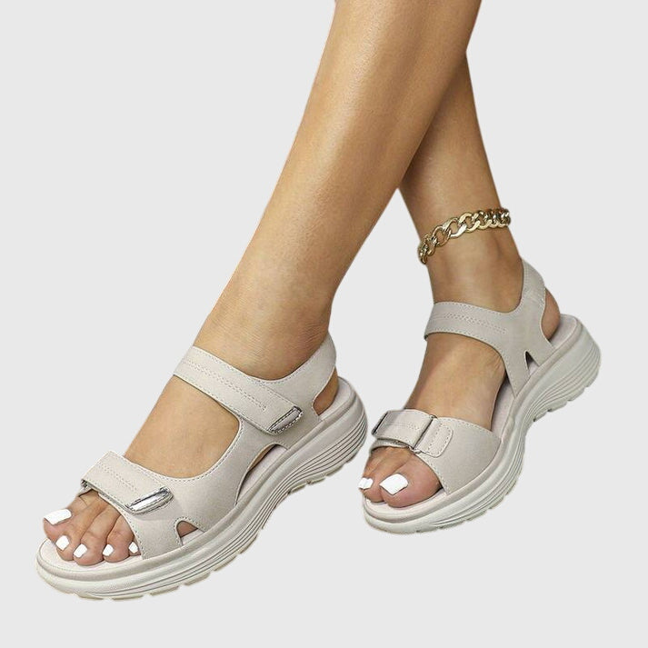 A woman in beige adjustable strap sandals standing steady and relaxed on a sunny path.