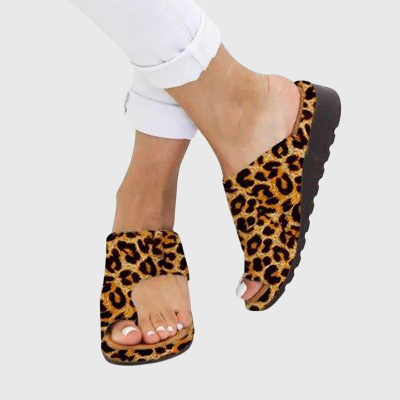 A woman in taupe toe-loop supportive sandals standing gracefully, feet cushioned and at ease.