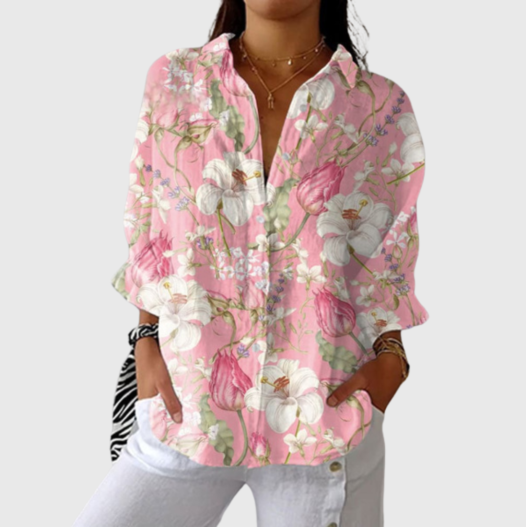 A woman wearing a loose colourful printed blouse with adjustable sleeves, styled with trousers for an easy day out.