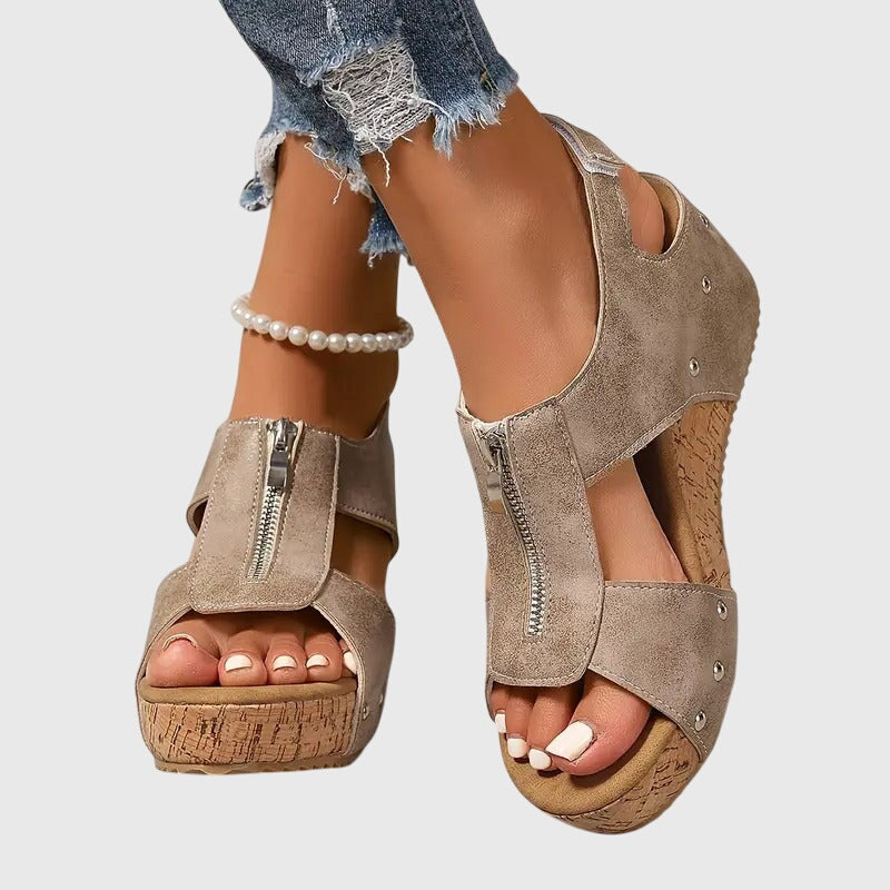 A woman wearing black zip-front wedge sandals with a cushioned footbed and open toe.