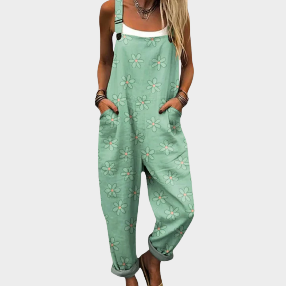 Woman wearing sage green dungarees with delicate white blooms, adjustable straps, feminine and relaxed.