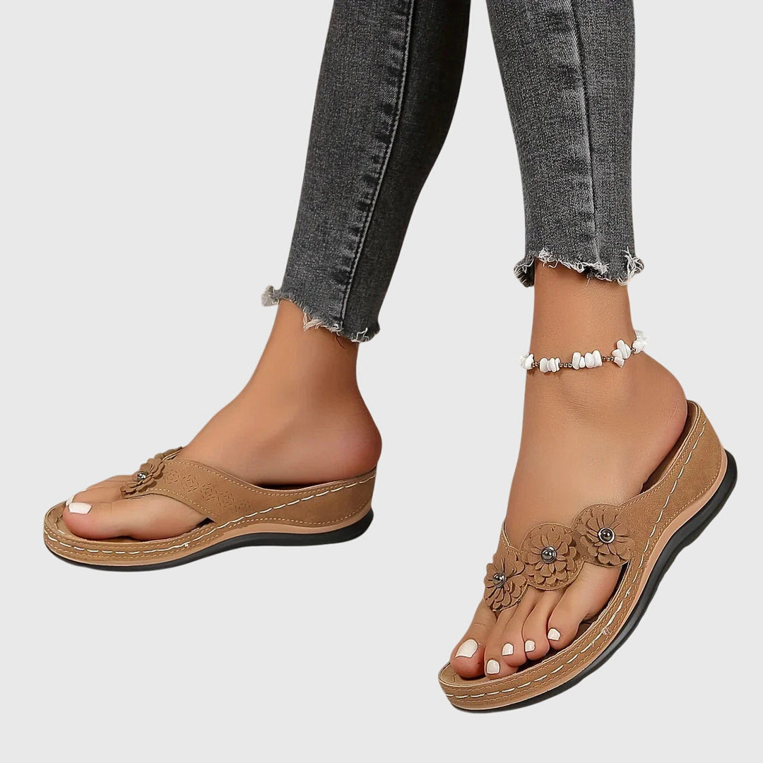 A woman wearing navy cushioned flip-flops with a supportive insole and open-front design.