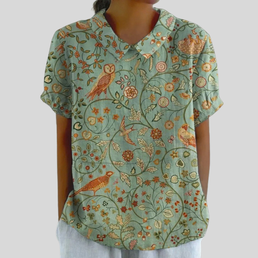 A woman wearing a flowing floral top with a polo collar, looking effortlessly groomed.