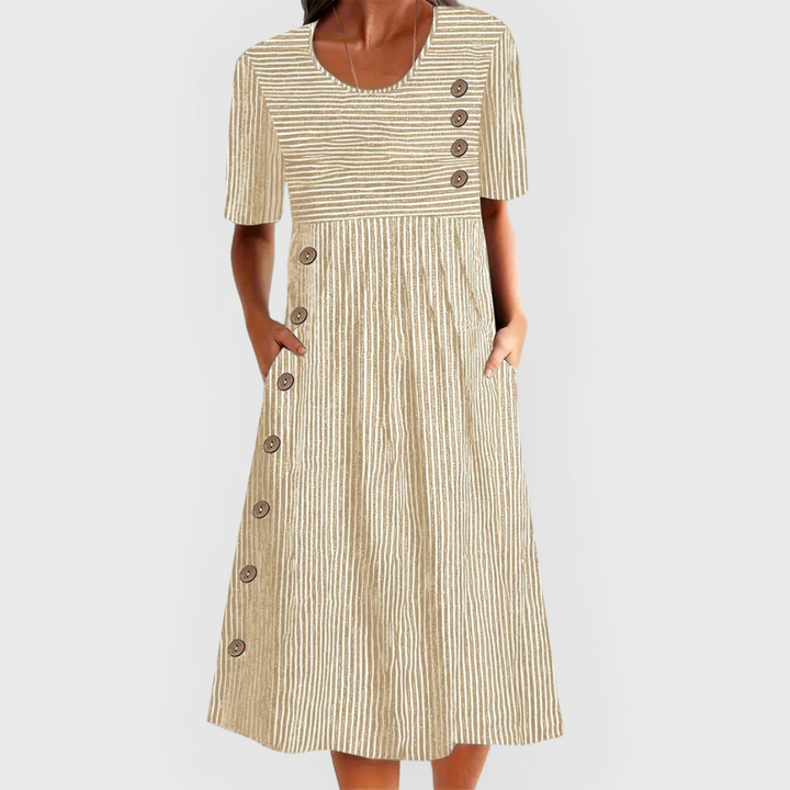 A woman wearing the Margaret striped midi dress with button details, standing outdoors on a bright day.