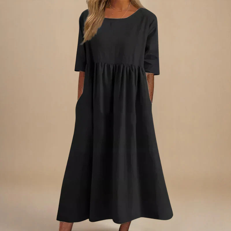 A woman wearing the Carmel flowing day dress with a gathered waist and elbow-length sleeves.