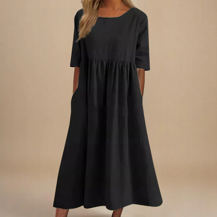 A woman wearing the Carmel flowing day dress with a gathered waist and elbow-length sleeves.