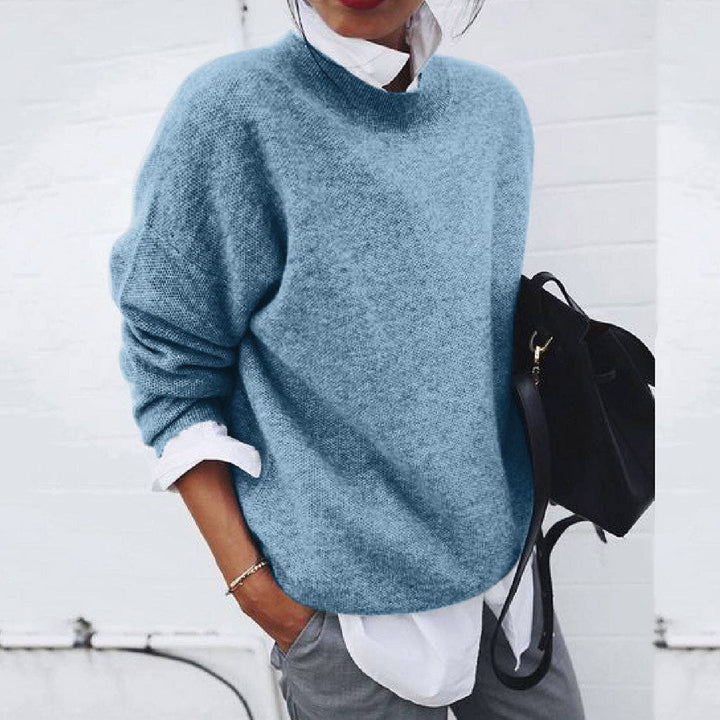 A woman wearing a soft mustard round-neck jumper with an elegant modern shape, relaxed and warm.