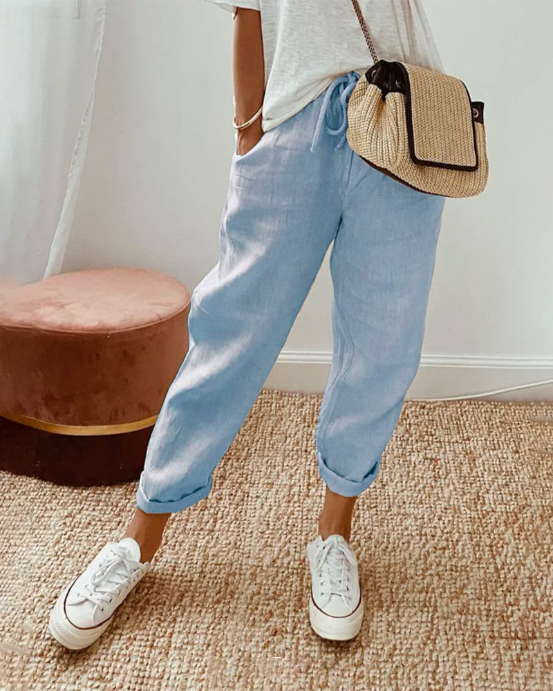 A woman wearing flowing elegant trousers with a soft elastic waist and deep pockets.