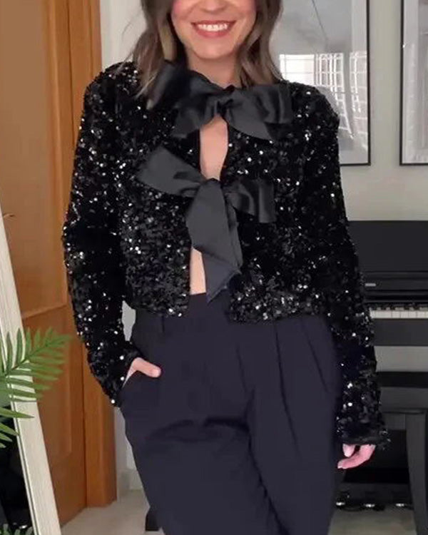 White shimmer blazer with large black bow detail and a cropped, structured cut