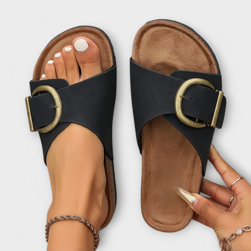 Black flat sandals with wide strap and decorative buckle detail